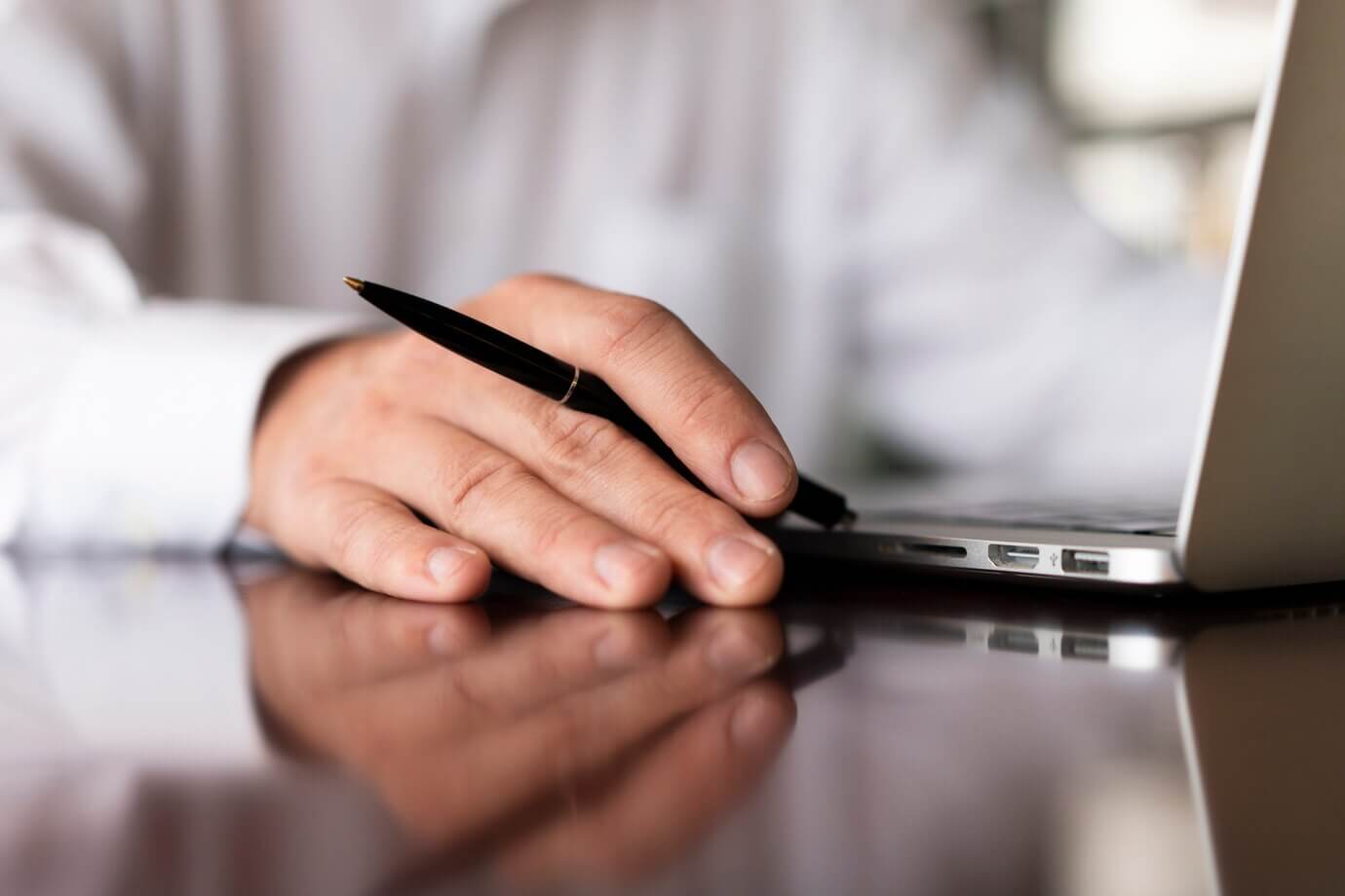 Homme travaillant devant son ordinateur un stylo à la main